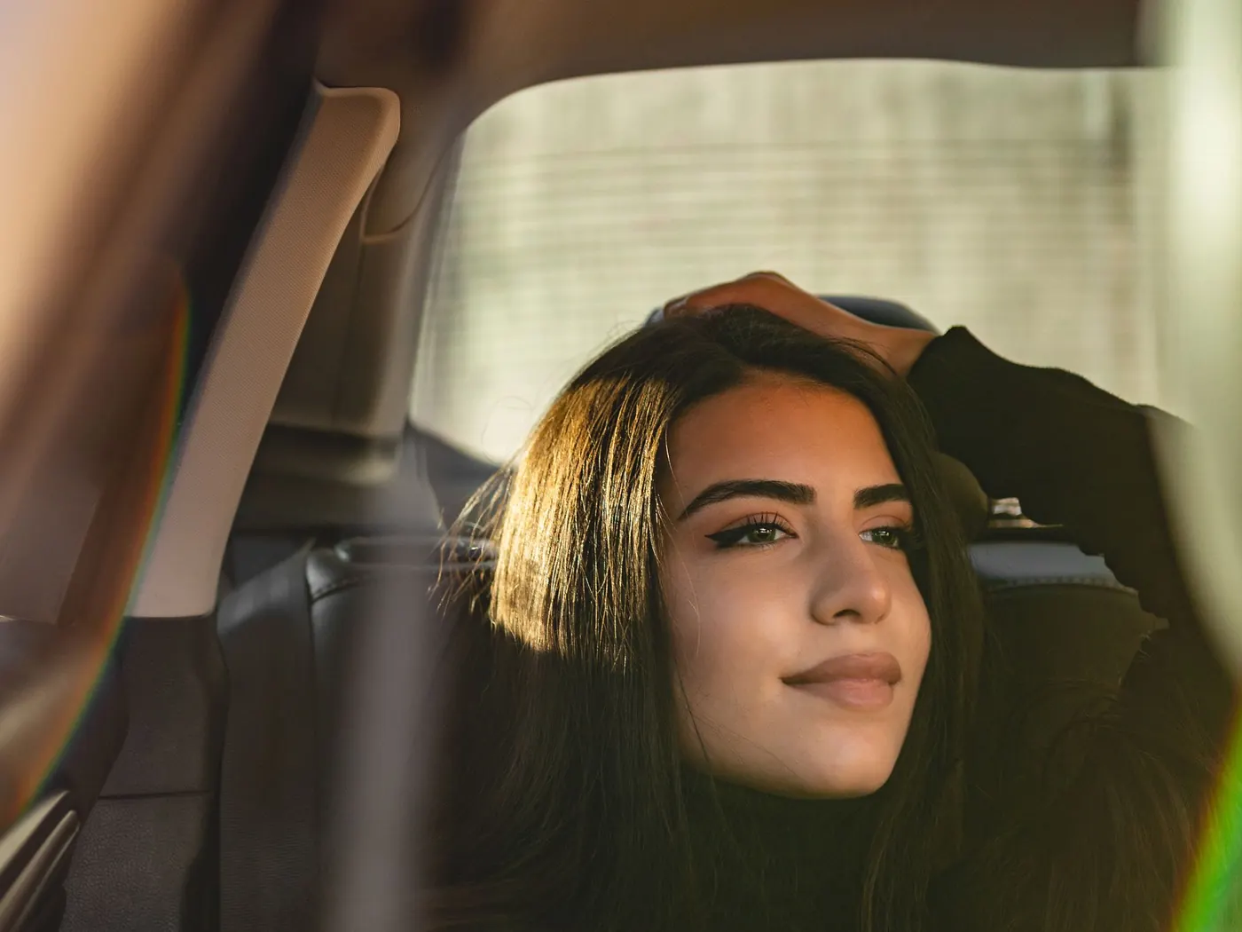 A passenger relaxing in the back seat of a chauffeured car